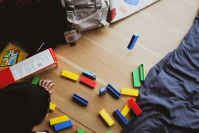 A child playing with colourful building blocks on a wooden floor
