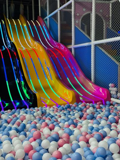 Colourful slides leading into a pastel pink and blue ball pit at an indoor play centre